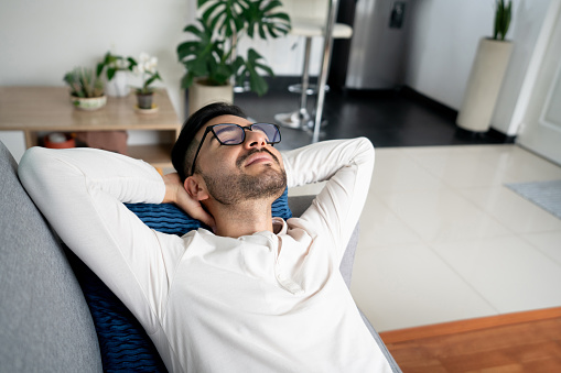 Latin American man relaxing at home and taking a nap on the sofa - lifestyle concepts