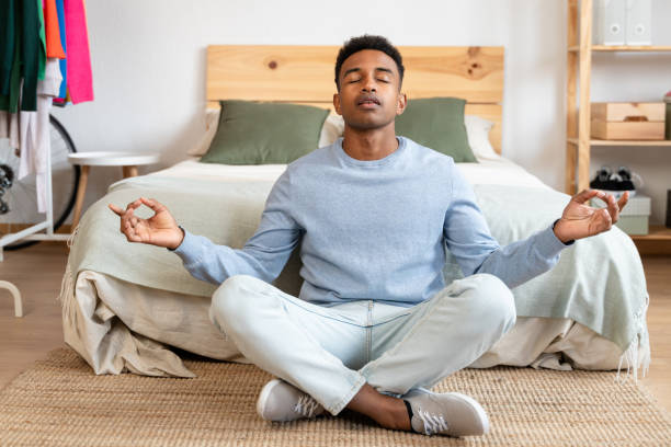 istock african american man meditating in lotus pose at home 1804802332