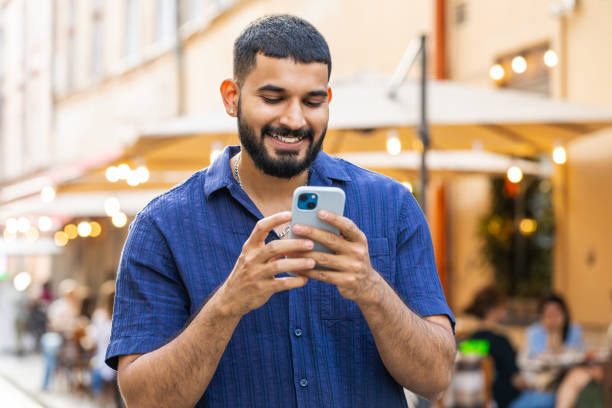 Indian man use smartphone typing text messages browsing internet finishing work chatting online