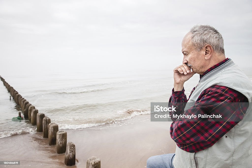 Thoughtful elderly man standing on the beach Thoughtful elderly man standing on the beach on a foggy day 60-69 Years Stock Photo