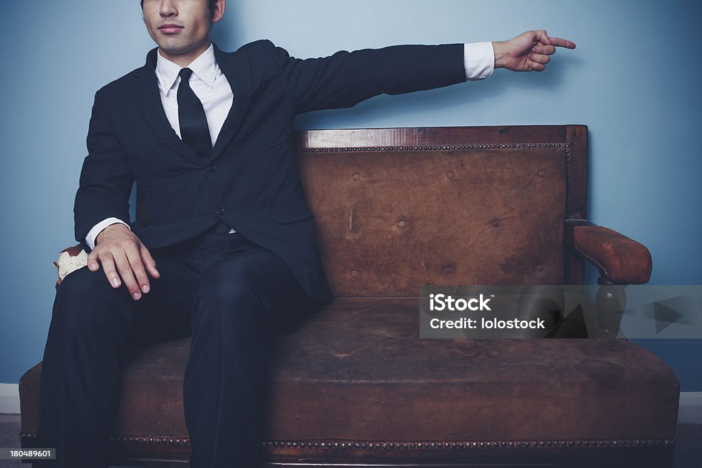 Geschäftsmann auf Couch zeigt rechts - Lizenzfrei Alt Stock-Foto