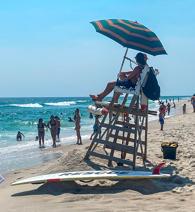 Fire Island, New York, USA - 22 July 2023: A lifeguard chair on the beach with a person sitting on it.