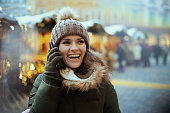 smiling woman at christmas fair in city talking on phone