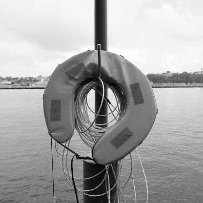 Flotation device on a pole with harbor view behind and overcast sky.