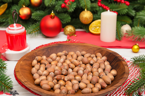 Hazelnuts in a wooden bowl on the background of the Christmas tree
