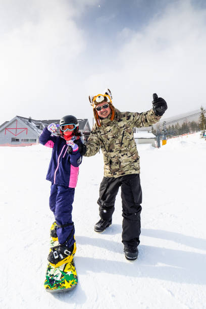 istock Man teaching young child to snowboard 1805074898
