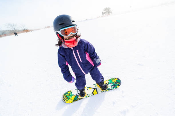 Young girl snowboarding for the first time A young Japanese girl trying snowboarding for the first time. japanese snowboarder stock pictures, royalty-free photos & images