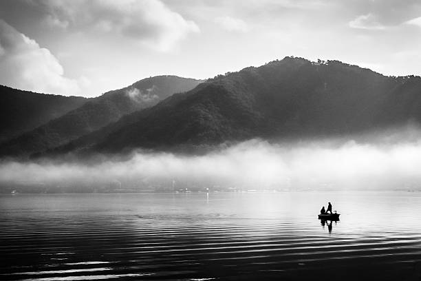 People doing their activities in the lake under the morning sun. Black and white.