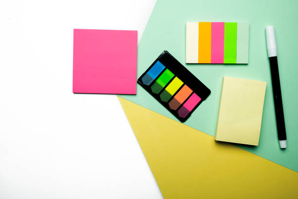 A colorful sticky note and notepaper with marker on a colored background