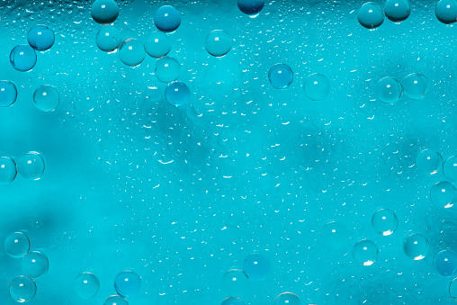 Abstract background with bubbles and water drops on a light blue, in closeup. Full frame