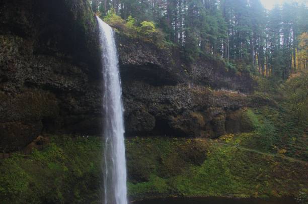 istock Side view of waterfall flowing down mossy rock face 1805180662