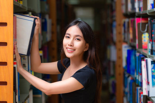 istock Asian woman student read text book in her university library 1805190843