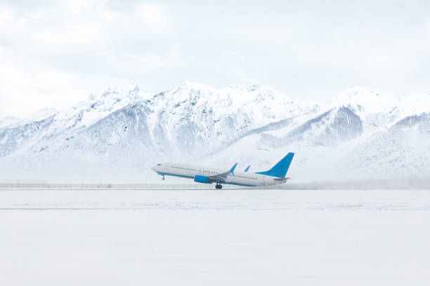 start eines passagierflugzeugs in einem heftigen schneesturm vor dem hintergrund hoher, malerischer schneebedeckter berge - airfield mountain snow airport stock-fotos und bilder