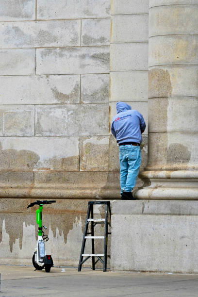 Washington, D.C., USA - November 20, 2023: An LSR Refinishing employee scrubs off “painted hands” graffiti placed there by protesters who defaced the building during a demonstration calling for a ceasefire in the Israel-Hamas war earlier in the week.
