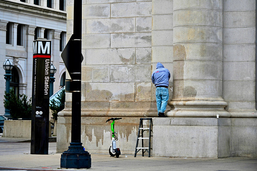 Washington, D.C., USA - November 20, 2023: An LSR Refinishing employee scrubs off “painted hands” graffiti placed there by protesters who defaced the building during a demonstration calling for a ceasefire in the Israel-Hamas war earlier in the week.