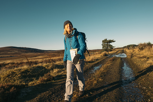 Woman hiking a long distance trail called the Dava Way which follows an old railway track from Grantown on Spey to the town of Forres in the Moray region of Scotland. Part of a series.