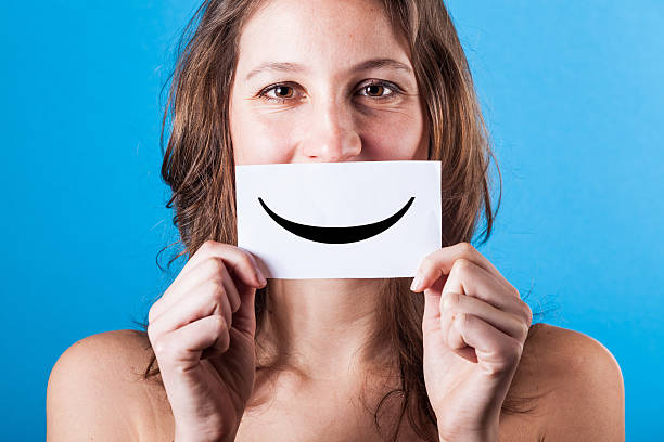 istock Young Woman with Smiley Emoticon on Blue Background 180526831