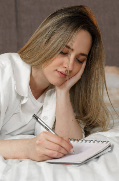 istock A young beautiful woman lies on the bed and makes notes in a notebook. 1805272925