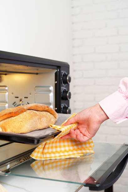 istock Woman's hands taking fresh bakery out of mini oven 1805310564