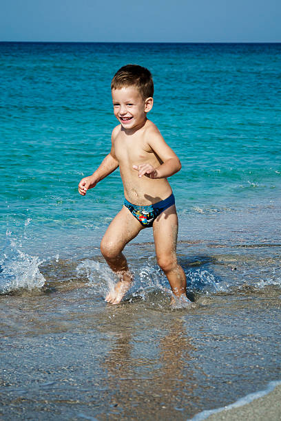 istock Cute three years child boy is running in sea 180532263