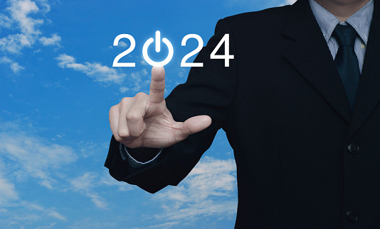 Businessman pressing 2024 start up business flat icon over blue sky with white clouds, Business happy new year 2024 cover concept