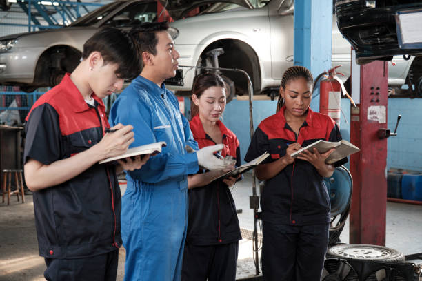 A supervisor engineer is training mechanic workers about car repair at a garage.