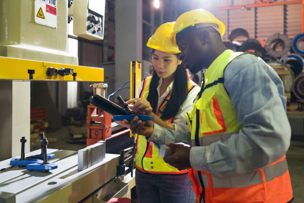 istock Two individuals are busily engaged with operating a large machine within a bustling factory setting. 1805365022