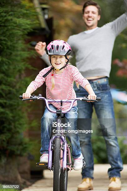 Father Teaching Daughter To Ride Bike In Garden Stock Photo - Download Image Now - 20-29 Years, 6-7 Years, Achievement