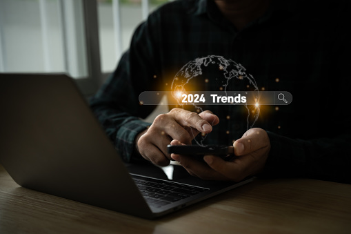 Trends 2024 year concept. Man using mobile laptop and showing virtual search engine bar with 2024 trends wording for marketing monitor and business planning in new year. Technology new year concept.