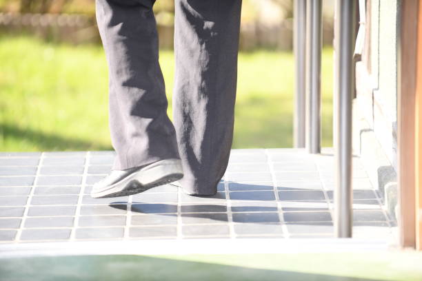 The feet of a senior woman who descends the entrance stairs and goes for a walk
