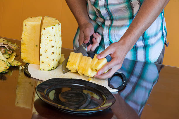 istock Teenager cutting or peeling a pineapple 180542380