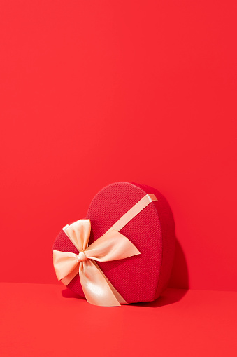 Red heart shaped gift box on red background with copy space for holidays and special days