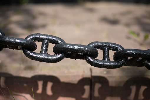 Heavy thick industrial chains laying on a stripped surface. Close up, wide horizontal composition.