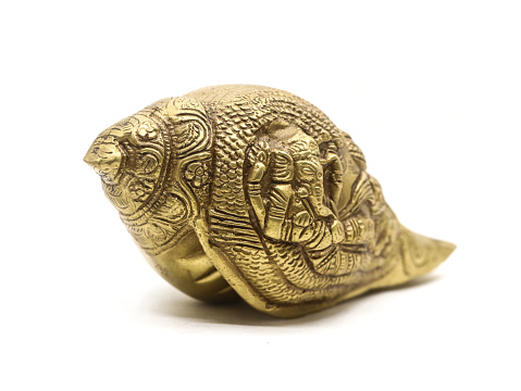 antique ganesha sculpture handcrafted with details on a religious conch shell made of brass used in temple and religious rituals isolated