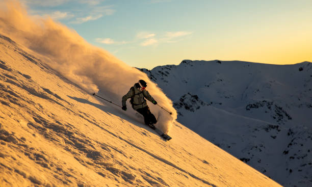 Back country skier riding big mountain slope at sunset