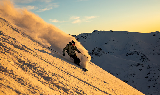 Free skier riding big mountain slope at golden hour