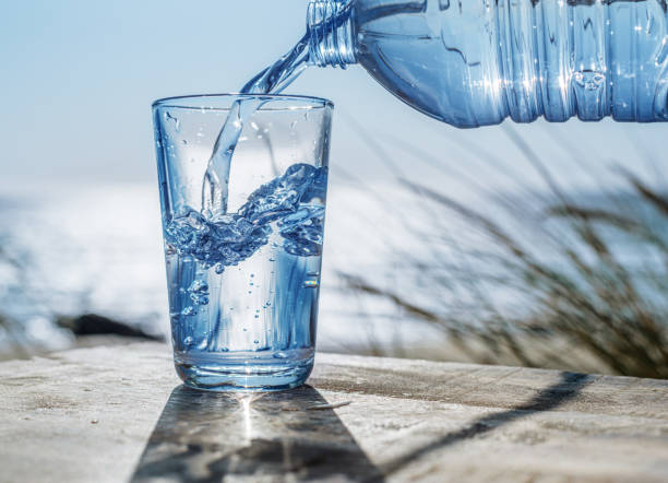 istock Pouring water into a glass from plastic bottle. Nature background. 1805448312