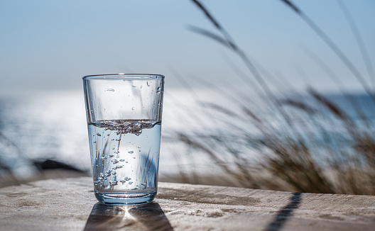 Pouring water into a glass from plastic bottle. Nature background.