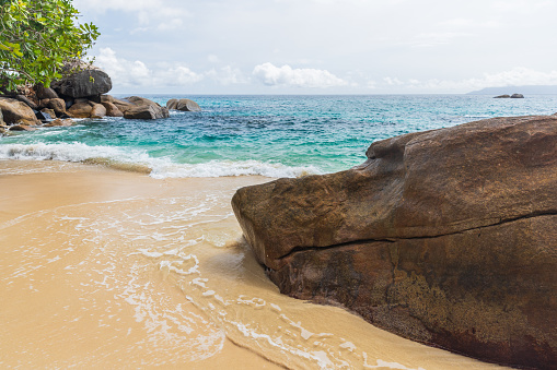 Sunset Beach, Mahe island, Seychelles. Coastal landscape with wet rock and ocean water on a clooudy summer day