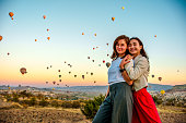 Female tourists who enjoy watching hot air balloons flying in the sky during their vacation enjoy the holiday and the view by dancing and having fun with each other