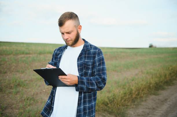 istock Farmer in a plaid shirt controlled his field and writing notes. 1805458226
