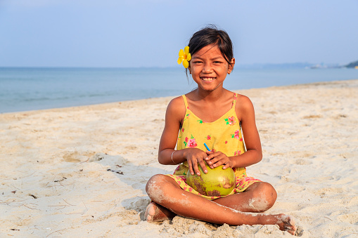 Cambodian little girl holding coconut on the beach, Cambodia