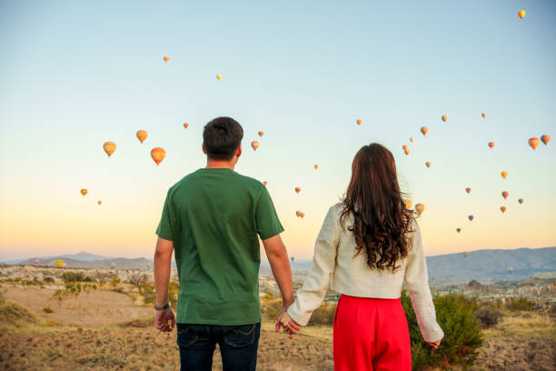 touristen genießen es, während ihres urlaubs heißluftballons am himmel fliegen zu sehen und genießen den urlaub und die aussicht - female silhouette beautiful professional sport stock-fotos und bilder