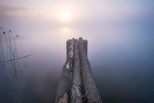 A wooden jetty in the pond on a foggy day