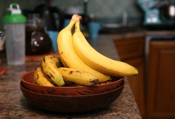 istock A bunch of bananas lying on a solid kitchen table. Sweet ripe bananas with yellow skin. Kitchen Scene with Bananas and Mixed Fruits Hand of ripe bananas in kitchen countertop 1805481988