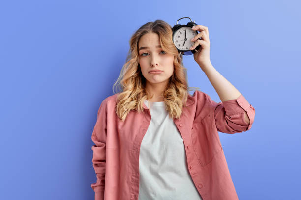 istock Sleepy woman with alarm clock attached to head 1805500060