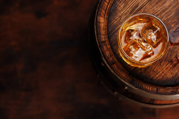 istock Whiskey glass with ice on a rustic barrel, a classic sip 1805513617