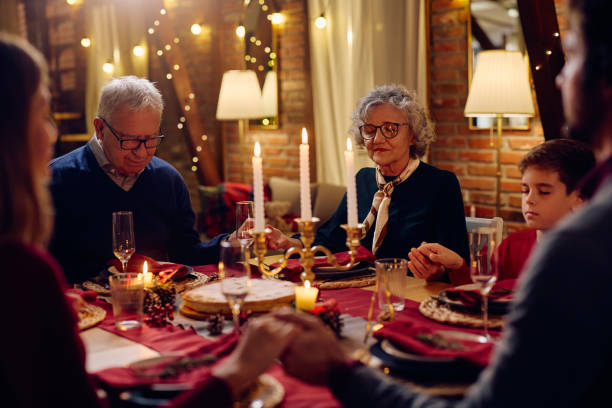 istock Extended family praying during Christmas dinner at dining table. 1805518223