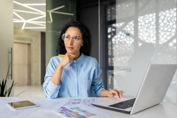 istock Serious and pensive Latin American woman inside the office works with documents and bills, contracts, reports, business woman thinks about decisions and plans future achievements 1805543711
