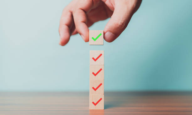 istock Checklist, Task list, Survey and assessment. Quality Control. Goals achievement and business success. Hand holding Check mark on wooden blocks for complete check list. 1805546956